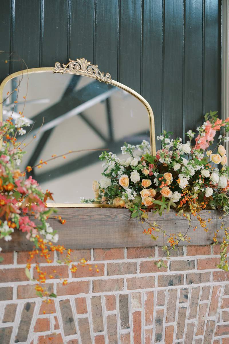 Large gold mirror styled on fireplace mantle with florals
